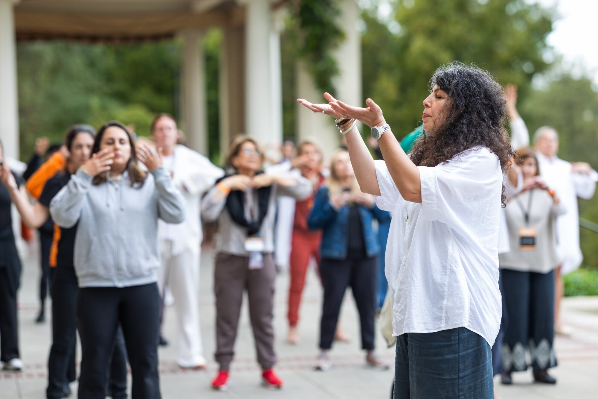 Armineh Turgeon guiding a group in breath and movement outdoors, palms open