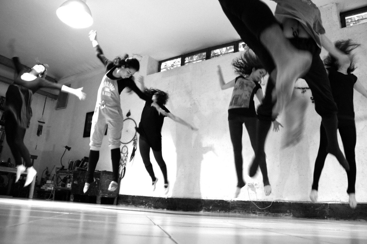 A group of dancers leaping, in black and white