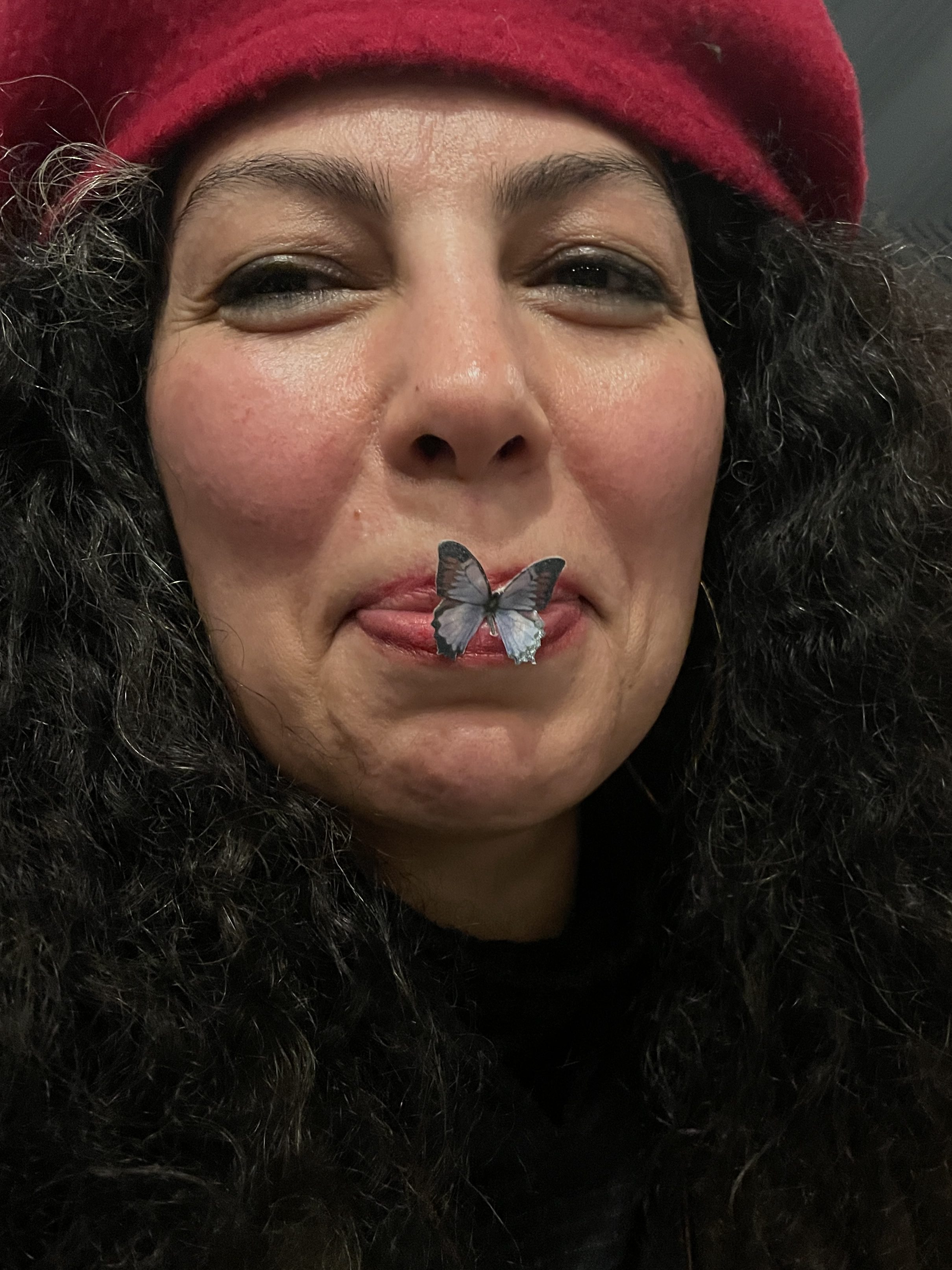 Armineh in a red beret, a small blue butterfly resting on her closed lips