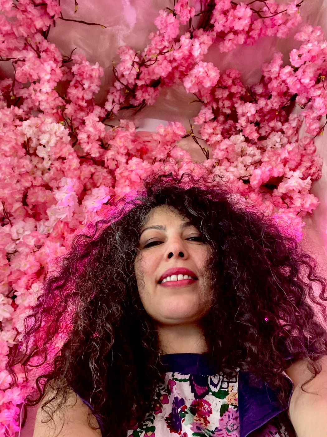Armineh smiling beneath a canopy of pink cherry blossoms