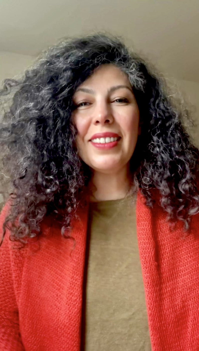 Armineh smiling warmly, in an orange knit jacket