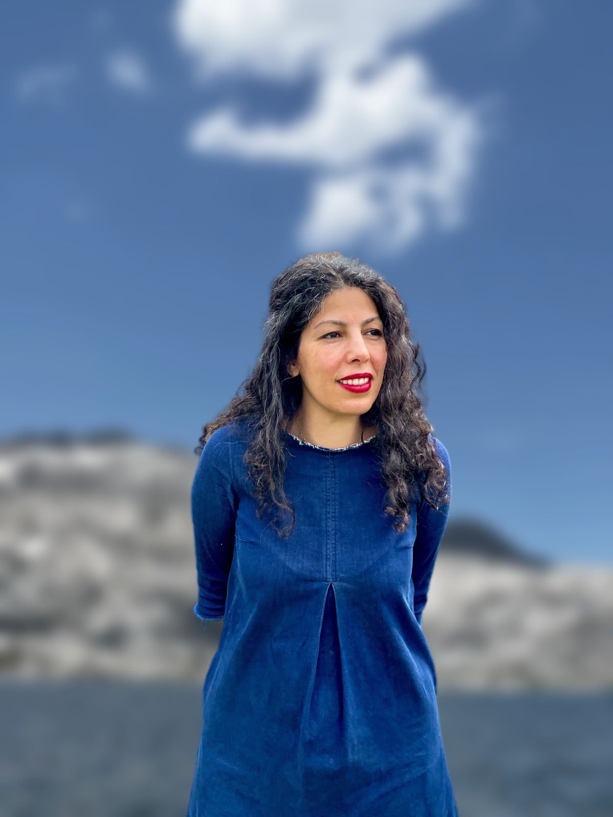 Armineh in a blue dress under an open sky
