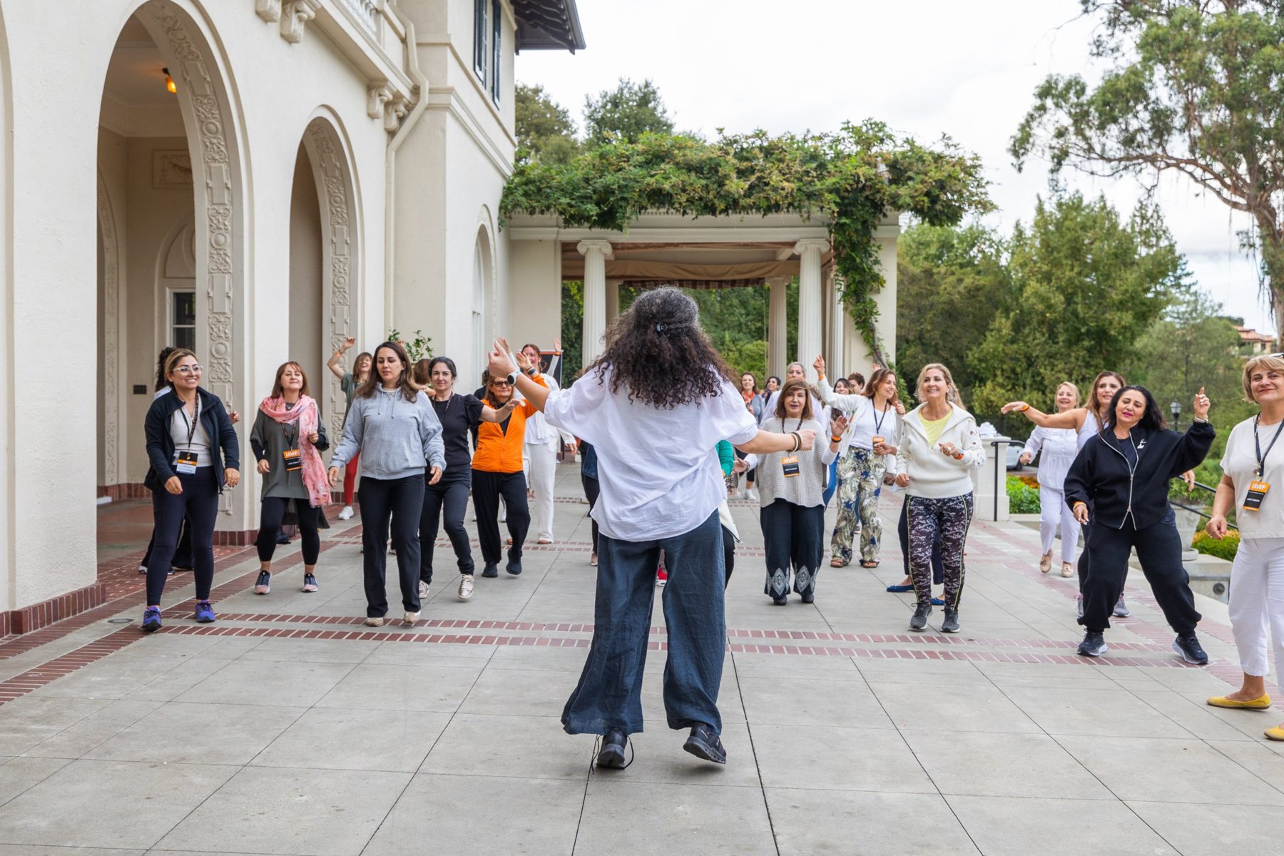 Armineh, seen from behind, leading a joyful group outdoors