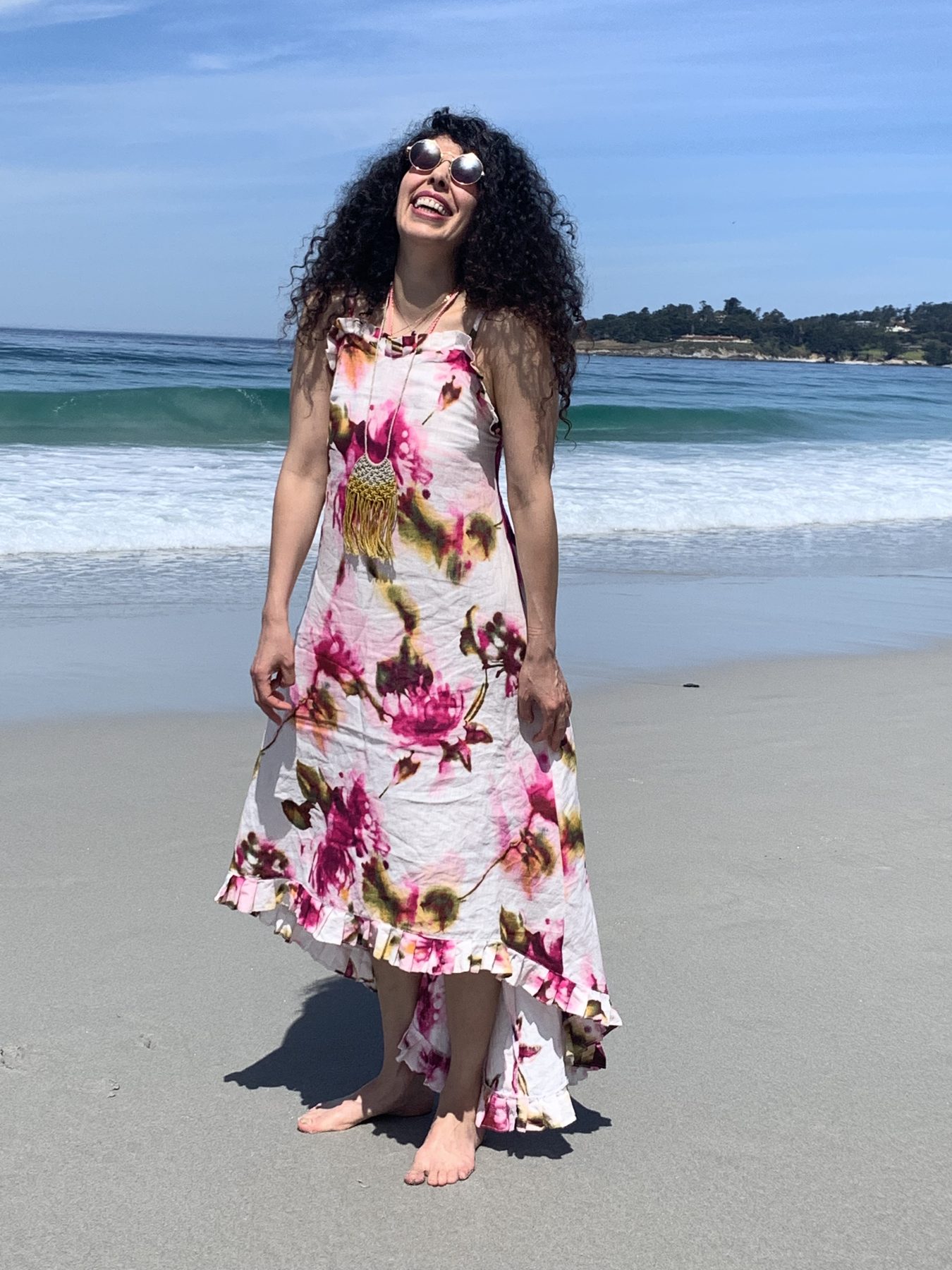 Armineh laughing barefoot on the beach in a floral dress