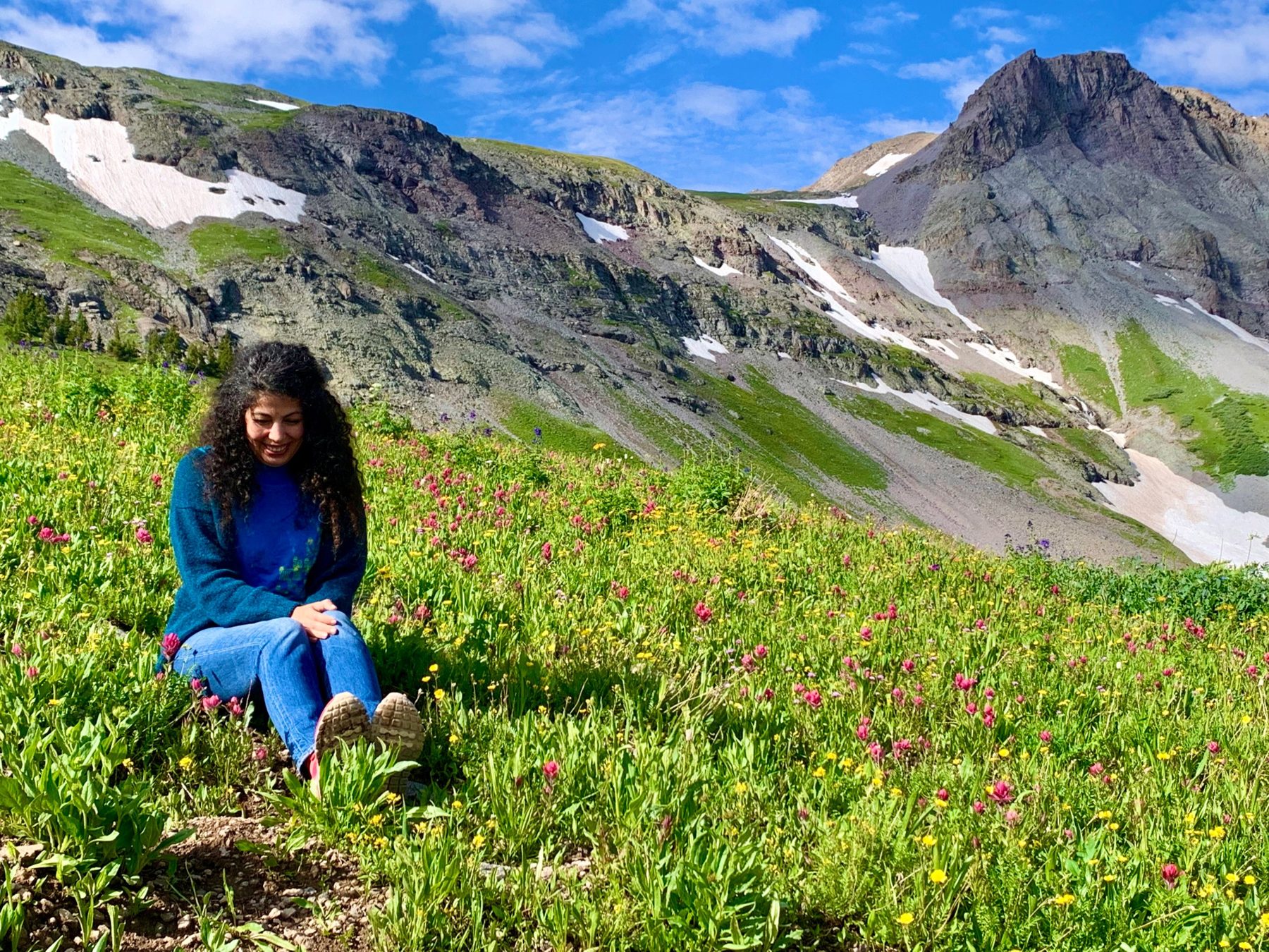 Armineh seated in a wildflower meadow below the mountains